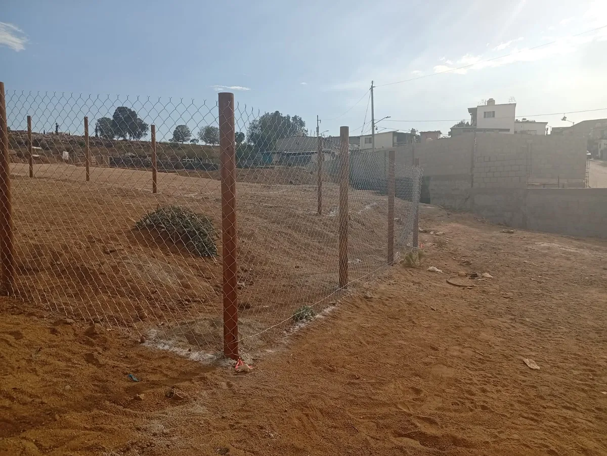 Cerco de malla ciclónica con postes de madera en un terreno de Ensenada