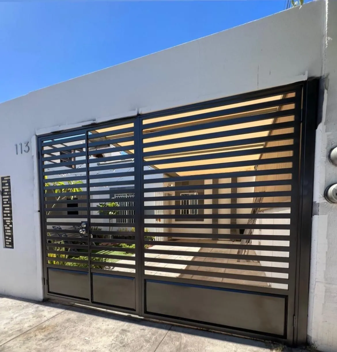 Portón de herrería negro sobre diseño en fachada residencial
